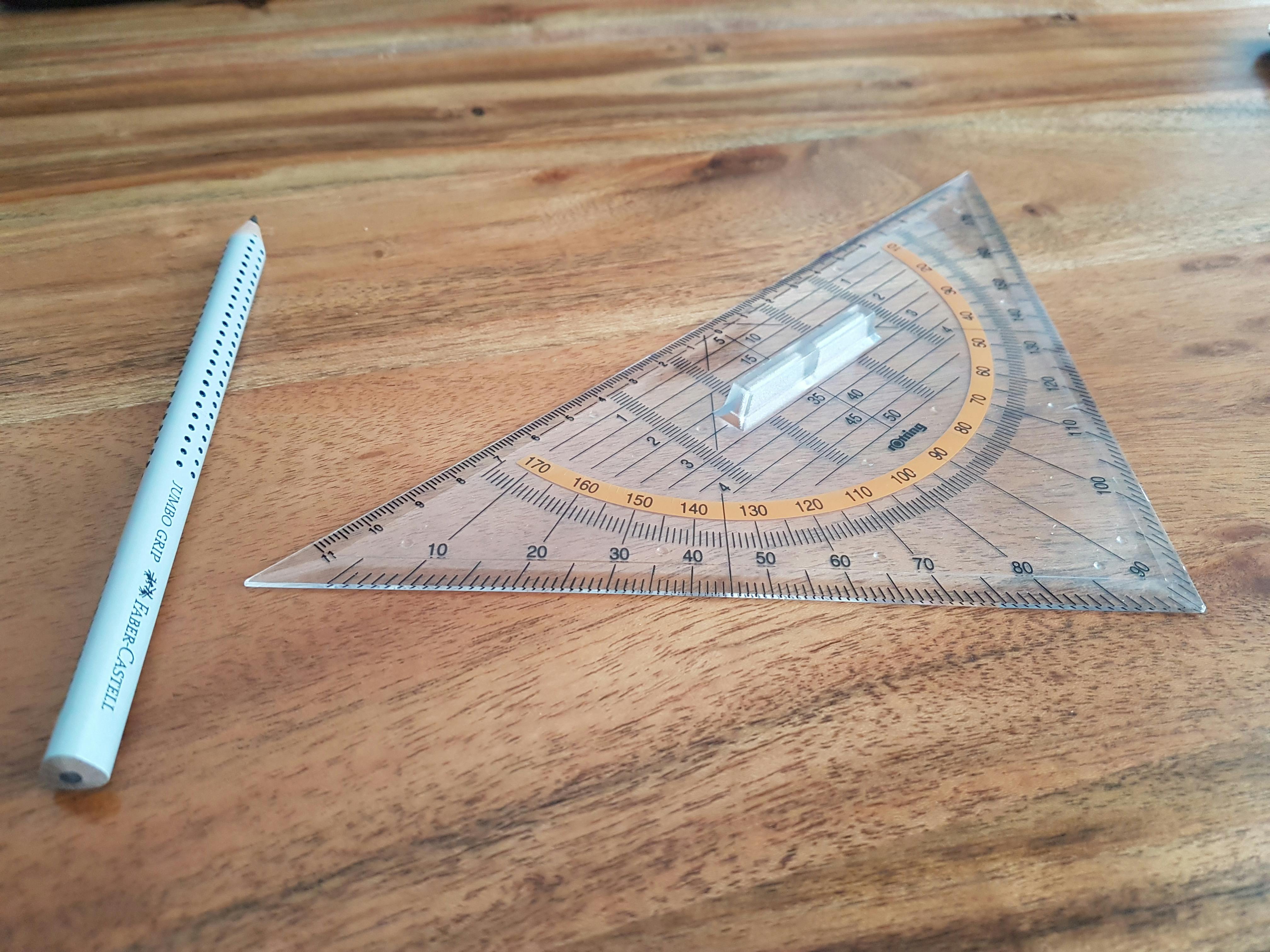 pexels-photo-376689-376689 A clear triangle ruler and Faber-Castell pencil on a wooden desk, perfect for precision drawing.